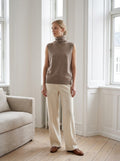 Model wearing the camel Merino Wool Sleeveless Turtleneck in a bright loft
