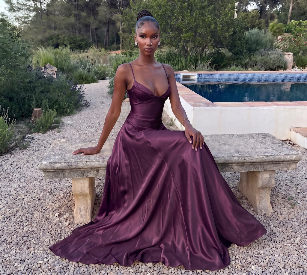 Deep purple satin maxi dress, seated on a stone bench