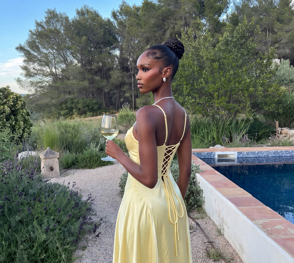 Butter yellow satin maxi dress worn in a garden, back view