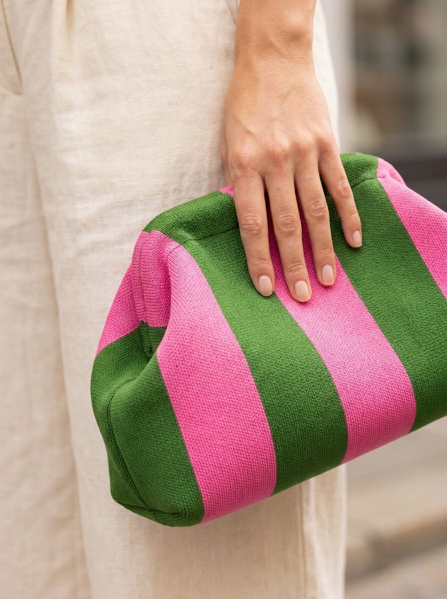 Close-up of hand holding the striped knit clutch